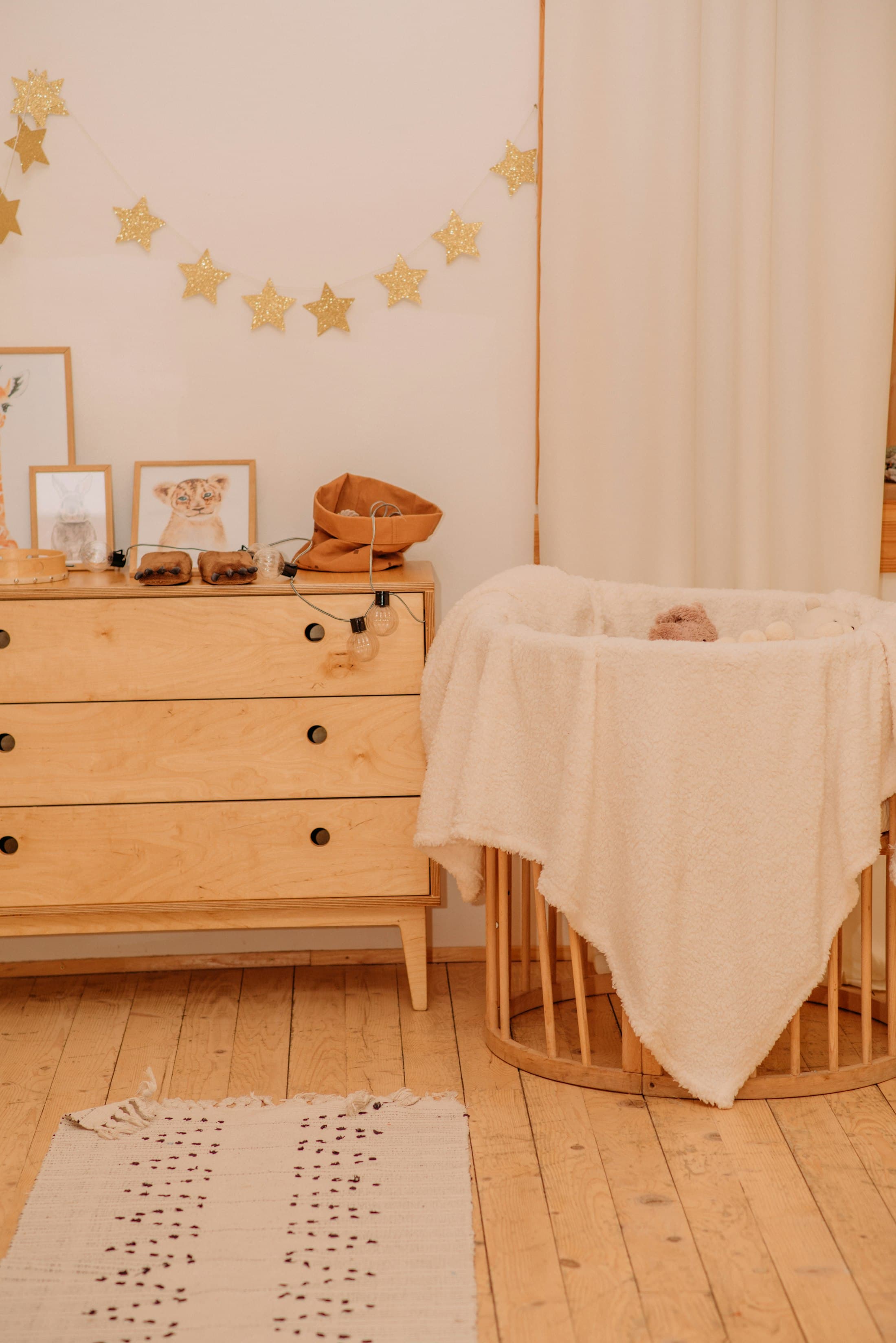 A warm nursery corner with a wooden dresser and bassinet
